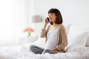 Image showing happy pregnant woman calling on smartphone at home