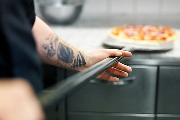 Image showing cook or baker hand with pizza on peel at pizzeria