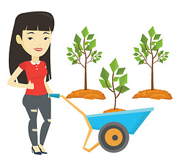 Image showing Woman pushing wheelbarrow with plant.