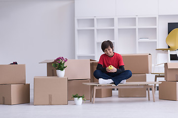 Image showing boy sitting on the table with cardboard boxes around him