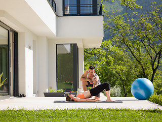 Image showing woman with personal trainer doing morning yoga exercises