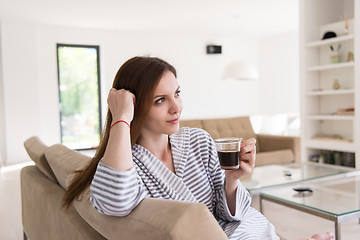 Image showing young woman in a bathrobe enjoying morning coffee