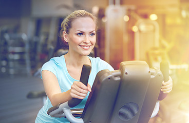 Image showing smiling woman exercising on exercise bike in gym