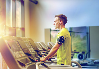 Image showing man with smartphone exercising on treadmill in gym