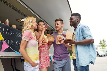 Image showing happy friends with drinks eating at food truck