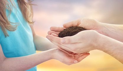 Image showing close up of father and daughter hands holding soil