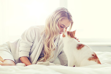 Image showing happy young woman with cat in bed at home