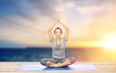 Image showing woman meditating in lotus pose on mat outdoors