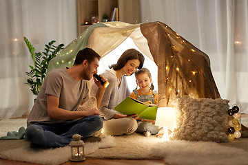 Image showing happy family reading book in kids tent at home