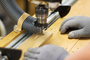 Image showing carpenter with drill press and board at workshop