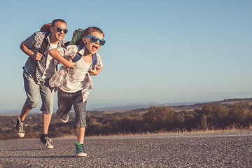 Image showing Father and son running on the road at the day time.