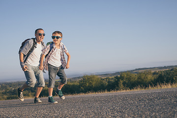 Image showing Father and son running on the road at the day time.