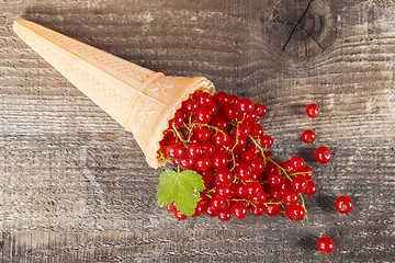 Image showing Red currant fruits in ice cream cone on wooden table