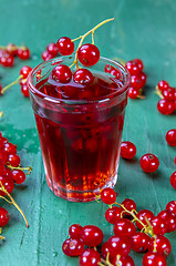 Image showing Red currant juice in glass with fruits on wood table