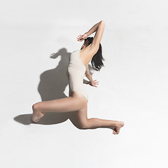 Image showing Young beautiful dancer in beige dress dancing on gray background