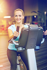 Image showing smiling woman exercising on exercise bike in gym