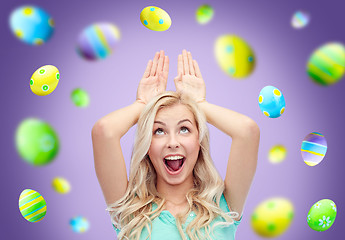 Image showing happy woman making bunny ears over easter eggs