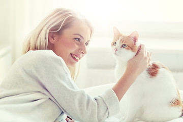 Image showing happy young woman with cat in bed at home