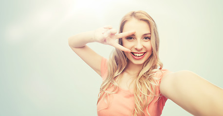 Image showing smiling woman taking selfie and showing peace sign