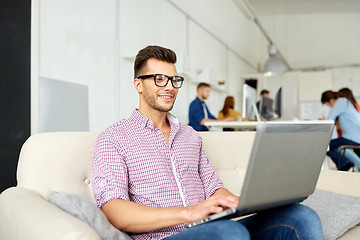 Image showing smiling man with laptop working at office