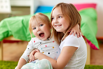 Image showing happy little girls or sisters hugging at home