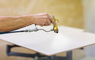 Image showing worker hand sprays urethane finish to board