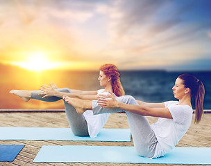 Image showing women doing yoga half-boat pose outdoors