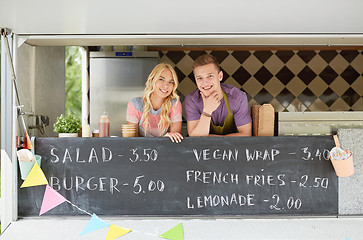 Image showing couple of happy young sellers at food truck