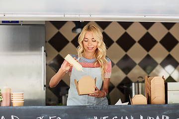 Image showing happy saleswoman making wok at food truck