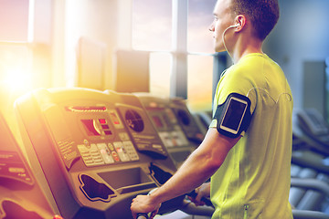 Image showing man with smartphone exercising on treadmill in gym