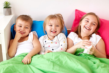 Image showing happy little kids having fun in bed at home