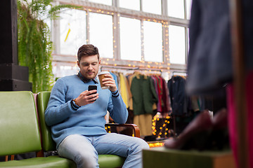 Image showing man with smartphone and coffee at clothing store