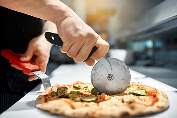 Image showing cook cutting pizza to pieces at pizzeria