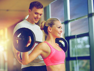 Image showing smiling man and woman with barbell in gym