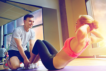 Image showing woman with personal trainer doing sit ups in gym