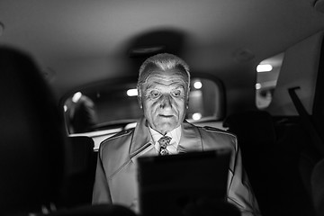 Image showing Businessman with a digital tablet sitting in the back seat of a car