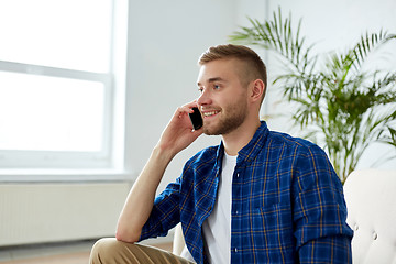 Image showing smiling young man calling on smartphone at office