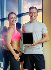 Image showing smiling young woman with personal trainer in gym