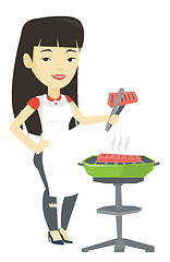 Image showing Woman cooking steak on barbecue grill.