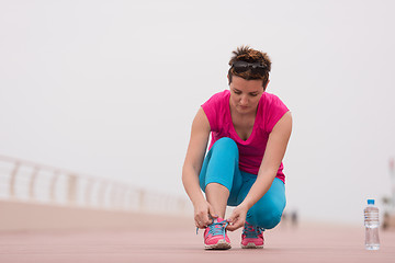 Image showing Young woman tying shoelaces on sneakers