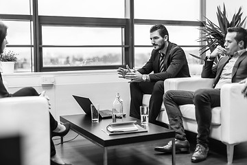 Image showing Businessmen interviewing female candidate for job in modern corporate office.