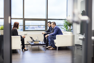 Image showing Businessmen interviewing female candidate for job in modern corporate office.