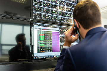 Image showing Stock trader looking at market data on computer screens.