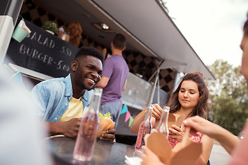 Image showing happy friends with drinks eating at food truck