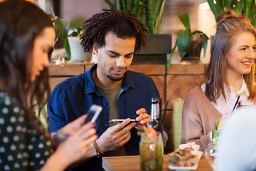 Image showing friends with smartphones eating at restaurant