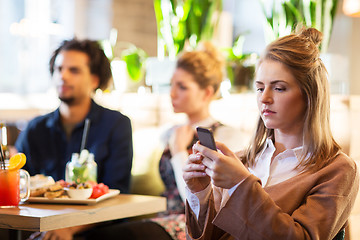 Image showing woman with smartphone and friends at restaurant