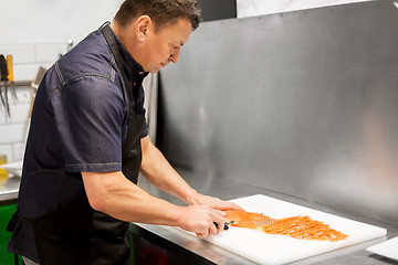 Image showing man slicing smoked salmon fish fillet