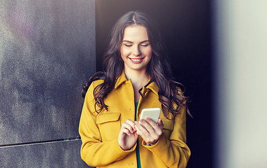 Image showing smiling young woman or girl texting on smartphone