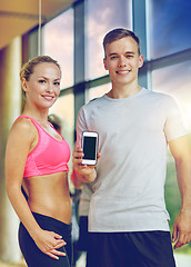 Image showing smiling young woman with personal trainer in gym