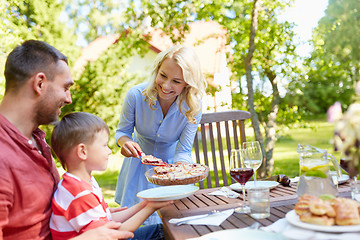 Image showing happy family eating pie at summer garden party